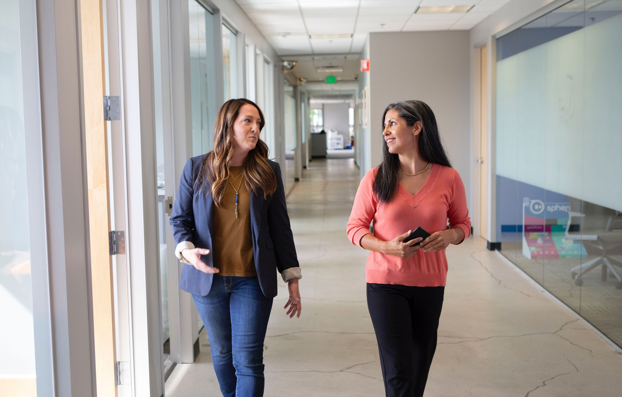 Professional women walking down a modern hallway