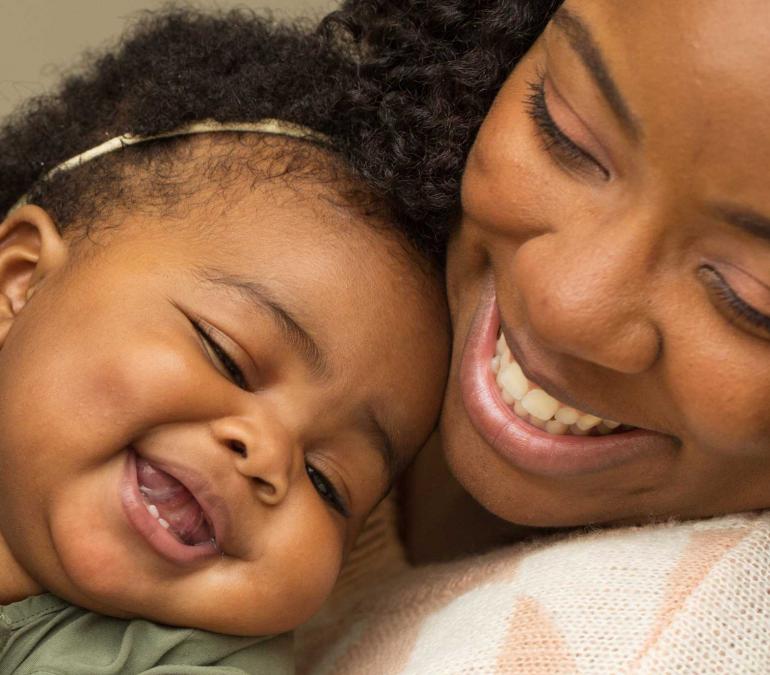Black mother holding laughing baby
