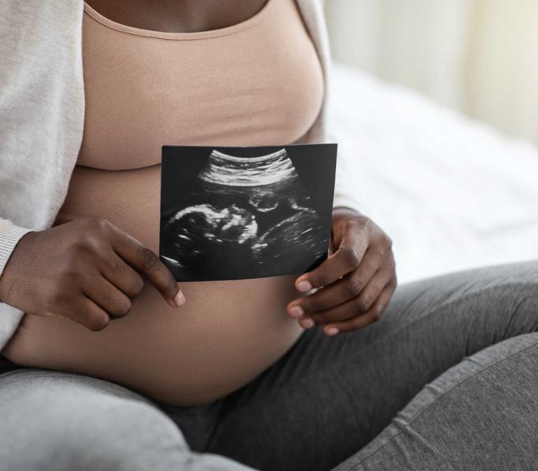 Pregnant Black woman holding a sonogram