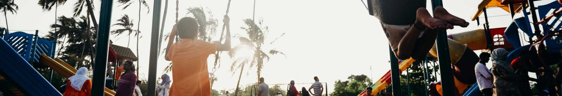 A cropped image of children on a playground with palm trees