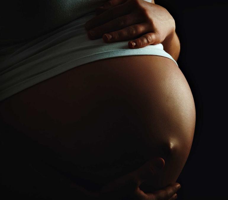 Closeup of a Black person's pregnant belly