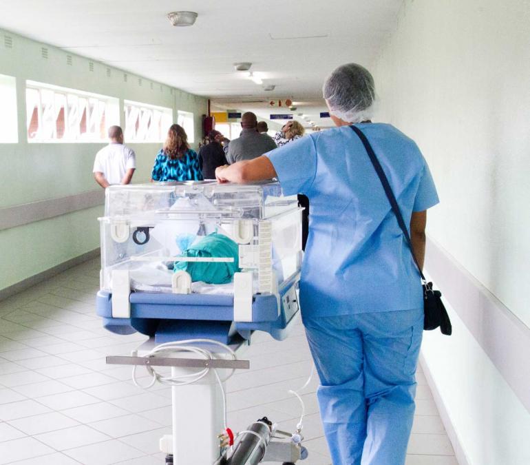 Medical professional pushing cart of supplies down a hallway